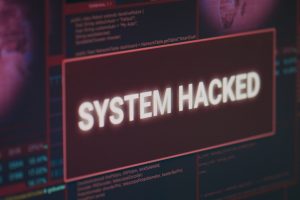 Computer monitor showing hacked system alert message flashing on screen, dealing with hacking and cyber crime attack. Display with security breach warning and malware threat. Close up.