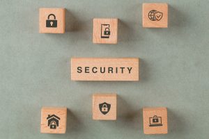 Security concept with wooden blocks with icons on sage color background flat lay. horizontal image
